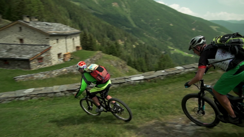 Mountain Biking Slow Motion Downhill Pan Right to Left: Passing Through Switzerland Village of Val Poschiavo