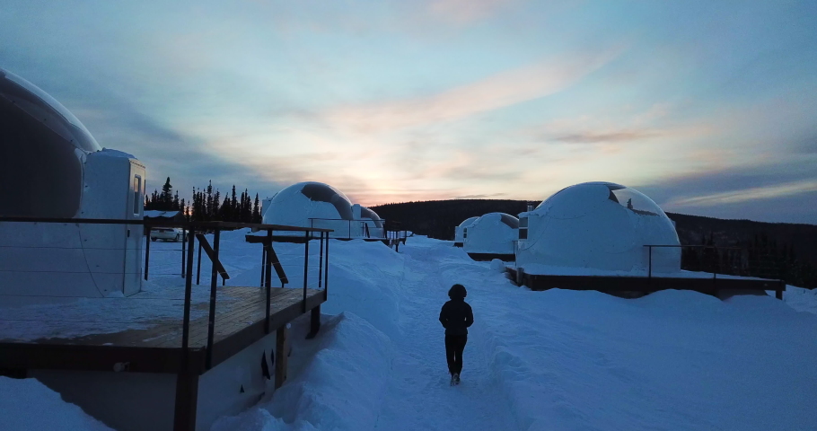 Aerial Forward: Woman Walking Through Igloos In Snowy Valley, Fairbanks, Alaska