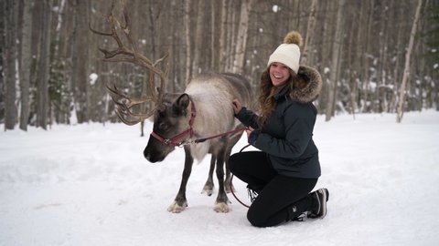 Up Close: Woman Happily Petting Reindeer In Snowy Forest, Fairbanks, Alaska