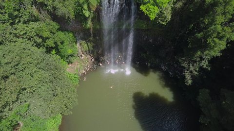 Aerial Backward: People Bathing Under Majestic Waterfall Among Lush Green, Atherton, Australia