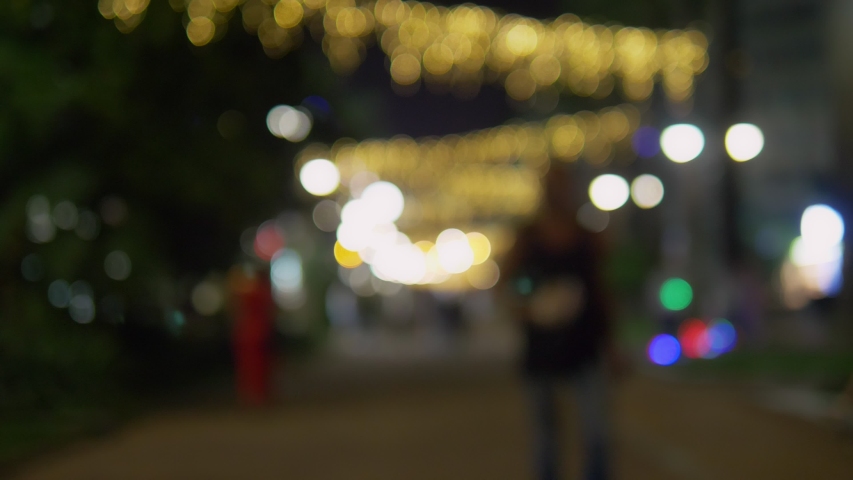 people walk through the night city. Abstract bright blurred background with bright bokeh. Nightlife concept in modern city