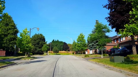Driving Approaching Stop Sign on Residential City Road With Lush Trees During Summer Day.  Driver Point of View POV Along Beautiful Sunny Suburban Street Slowing Down Past Stop Sign