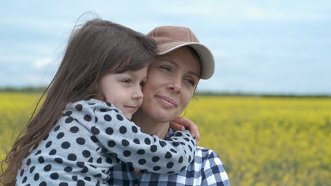Child hugs mother. Portrait of mother with daughter on a flowered field.