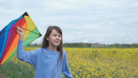 A child with a kite. A happy little girl runs with a kite through a field of canola.
