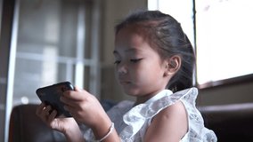 Asian girls play games in their mobile phones in the house