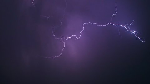 View of amazing lightning strikes on night dark sky in summer. Stormy sky with lightning flashing and thunder. Night thunderstorm clouds. Slow motion.
