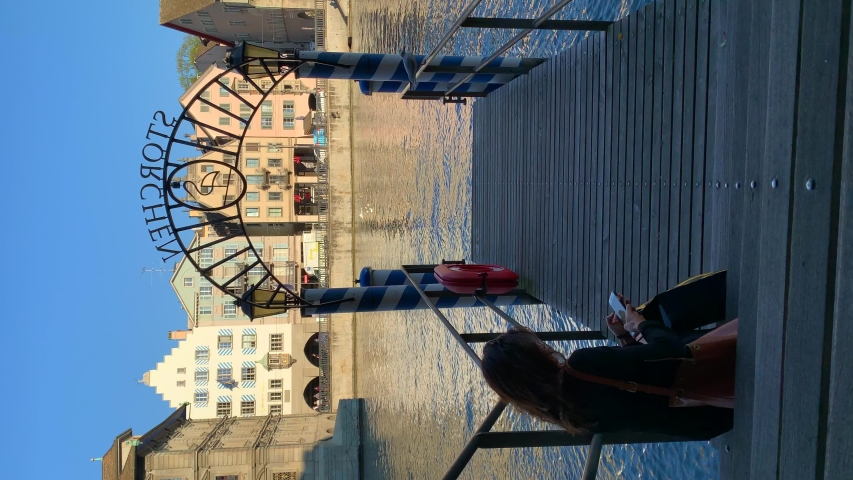 Vertical video of woman sitting on the pier looking towards the river Limmat in Zürich Switzerland