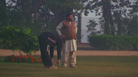 faisalabad, Pakistan - 12 11 2018: Two men are exercising on the grass of the park at morning