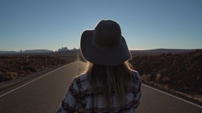 Woman loves USA, makes heart shape finger frame; Rear view of woman standing on long highway road leading to Monument Valley in USA. People travel America concept 