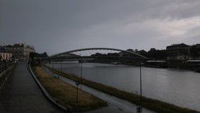Time lapse video 4k: City Embankment and Father Bernatka Bridge in Rainy Weather. Boats moving on the river. Krakow, Poland. 