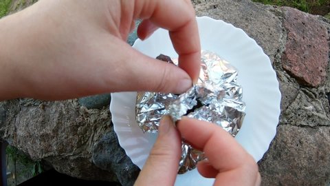Woman's fingers open the foil wrapped dish. Slow motion