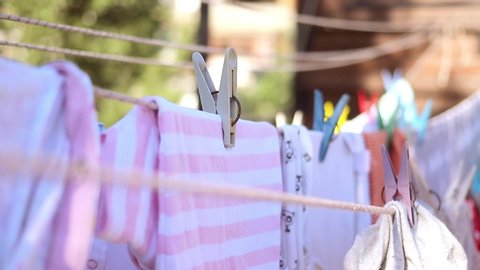 Clean baby laundry clothes dries on a rope with clothespins. Waving on a wind outdoor on open air.
