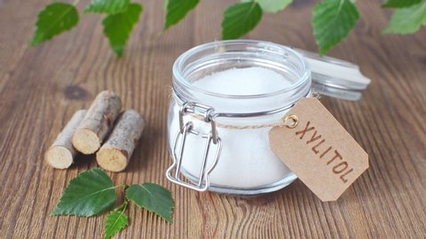 sugar substitute xylitol, a glass jar with birch sugar on wooden background