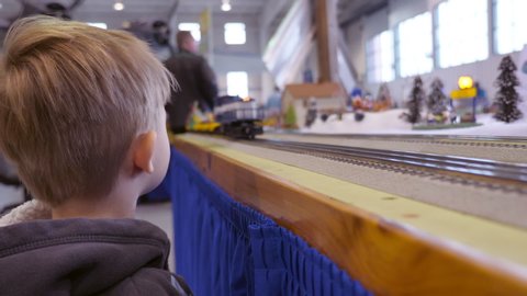 Young boy watches model train go by.