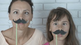 Family with a mustache. Funny mother and daughter grimace with false mustache. - Powered by Shutterstock - Get 15% off with code: PIKWIZARD15