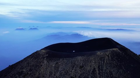 Guatemala volcano Acatenango and volcano Fuego aerial drone 4K video. Fly over Acatenango volcano crater where hikers are watching beautiful sunrise scenery. Aerial landscape panorama shot. 