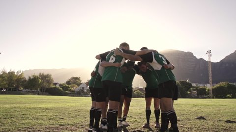Group of rugby players performing a war cry before the match. Rugby team standing in a huddle doing their war cry.