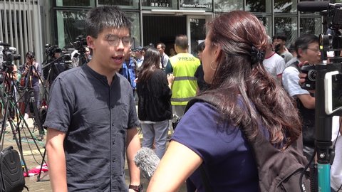 HONG KONG - 2 JULY 2019: Joshua Wong gives interview to international news media (BBC) in front of ransacked parliament building of Hong Kong (one day after July 1st storming of the building)