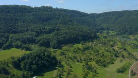 Aerial around the Reussenstein Castle in Germany.  Camera zooms inover a meadow, forest and mountainside in the background.