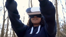 4K video clip of beautiful mixed race African American girl teenager female young woman using virtual reality VR headset in a forest woodland environment