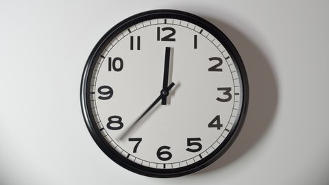 Closeup of White Clock Face in timelapse in daytime of office on white wall
