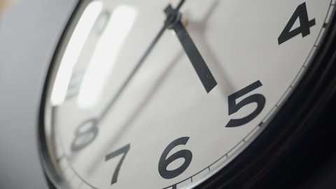 Closeup of White Clock Face in timelapse in daytime of office dark grey wall
