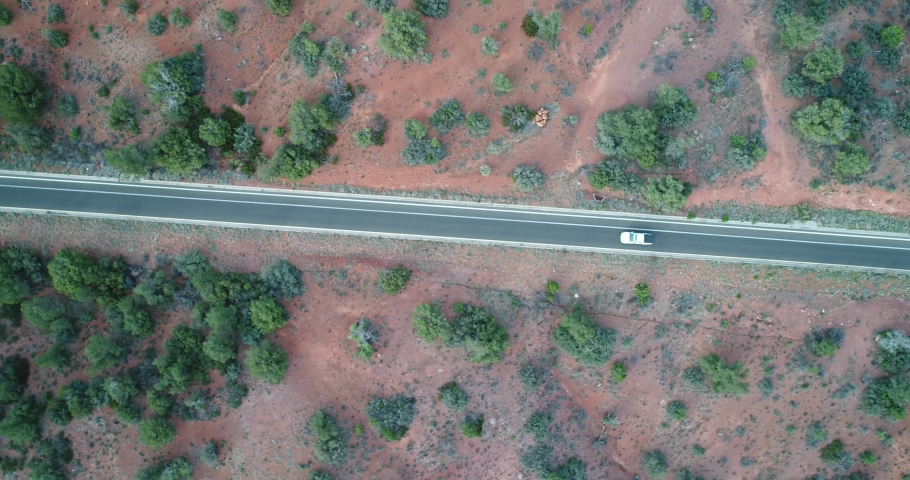 An aerial view of a car driving along State Route 179, a famous street that goes through the Oak Creek Canyon, Sedona and Flagstaff. The long, winding road passes through the desert.