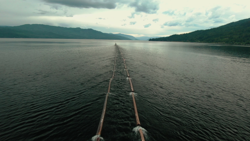 Aerial Drone Shot of Canadian Logging Tug Boat Pulling Logs & Timber Through Shuswap Lake, British Columbia, Canada. Logging Industry Forestry 