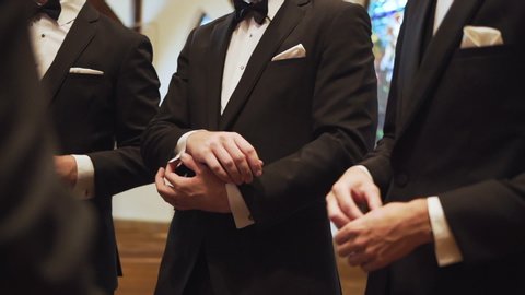 Toronto, Canada - 08 01 2018: Group of groomsmen putting on cufflinks in a church.