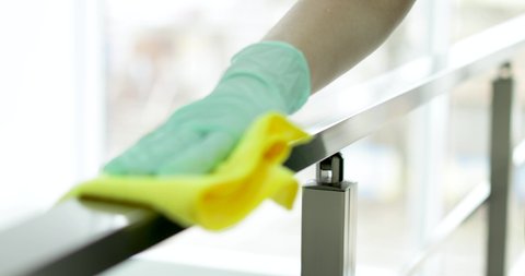Professional janitor cleaning handrail with rag indoors, closeup
