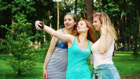 three female friends in Holi paints make funny faces for selfie photo