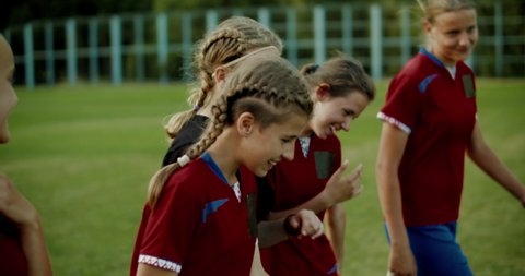 TRACKING Teenager kid girls soccer players talking and laughing after training. 4K UHD 60 FPS SLO MO