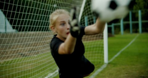 Young teenager girl soccer goalie diving to catch the ball during a match or practice. 4K UHD
