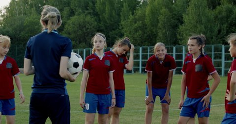 Female coach talking to kids during teenager girl soccer football team practice. 4K UHD 60 FPS SLOW MOTION