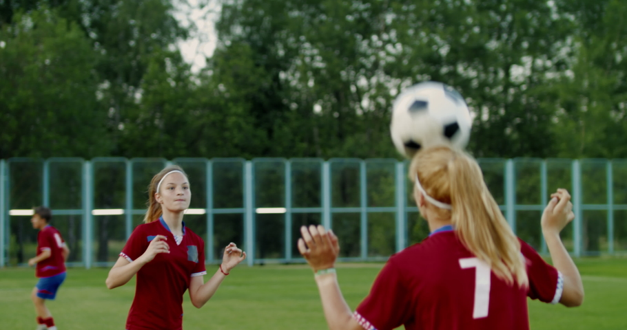 Young Caucasian teenager girl soccer football players heading the ball during practice session. 4K UHD