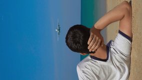 Vertical video. young man laying on a beautiful beach watch a landing airplane