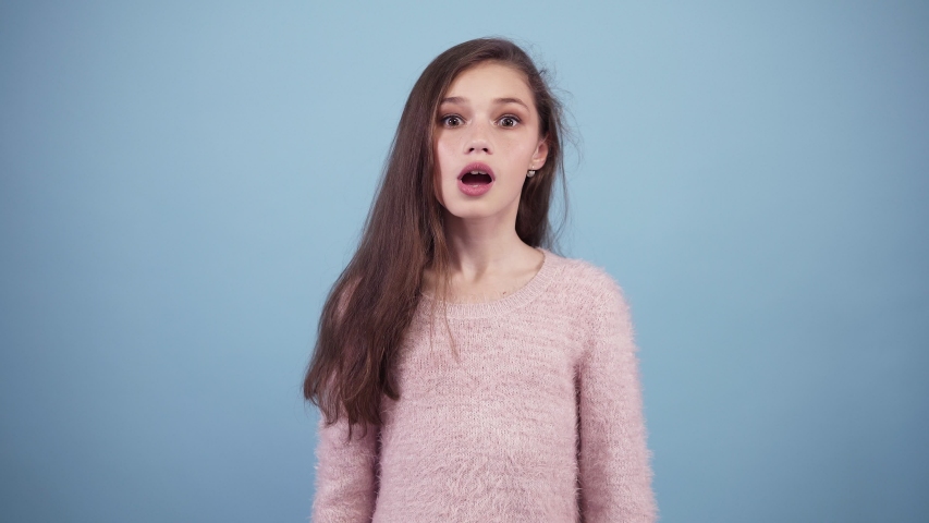 Really I can't believe it. Long haired girl excited, she is surprised and can't believe in. Covers the head with hands. Blue background isolated. Excited, funny and happy girl