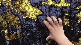 Gold shiny double side sequins sparkling background. Glowing glittering fashion sequined textile. Kids hands drawing on fabric with sequins.