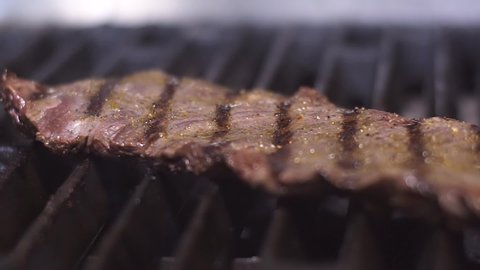 Steak is fried in the kitchen of the restaurant. Macro shot of a steak. Close shot of a steak. Meat is being cooked. The process of cooking steak in slow motion. The meat is grilled.