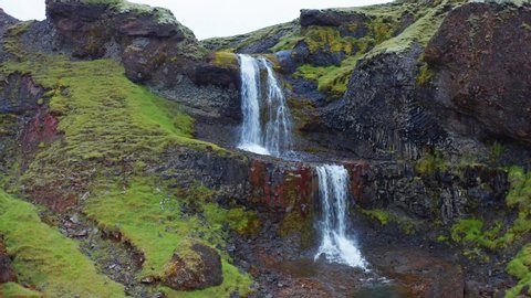 Beautiful midnight sun view of nameless waterfall on Rauda river. Nice green hills on the southern coast of Iceland at June. 4k drone forward video (Ultra High Definition).