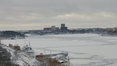 Right to left pan over frozen river of Stockholm to the city center during winter