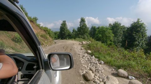 KATHMANDU, NEPAL - SEPTEMBER 2018: POV, Driving down an unpaved trail running across poorly rural Nepal, while driving in an old jeep. First person view of bumpy road trip towards Tibet.