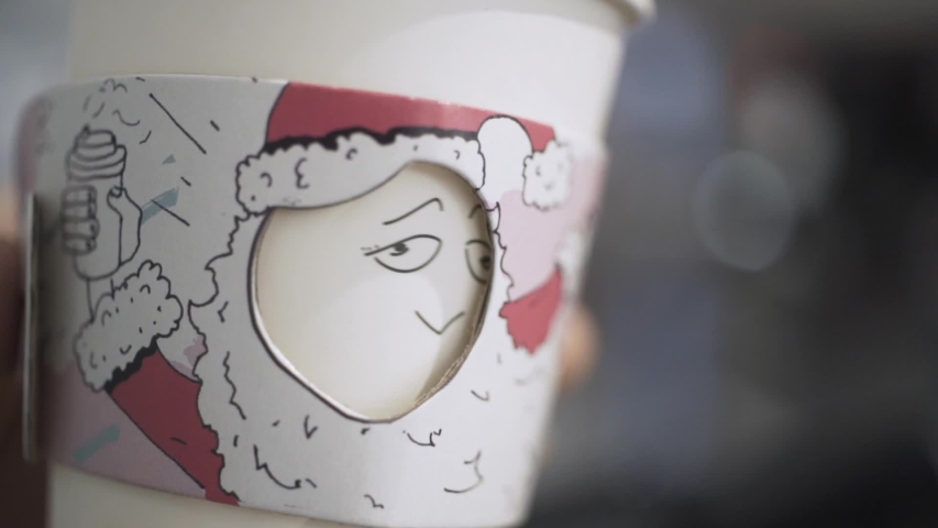 Close-up of beautiful and original styrofoam coffee cup with funny faces in the barista hand. Action. Drink tasty coffee and have a fun concept