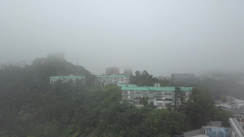 Flight over a misty Victoria Peak with housing in Hong Kong. Drone shot.