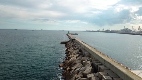 Aeria view of small lighthouse on breakwater wall at entrance to Barcelona port.