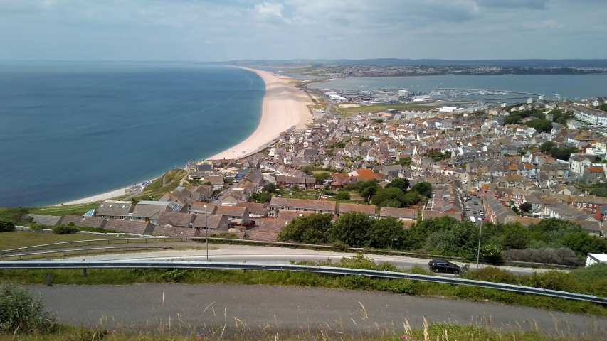 Pan over Chesil Beach and Portland Harbour which links Weymouth with Portland in Dorset England. The small town of Fortuneswell is in the foreground.