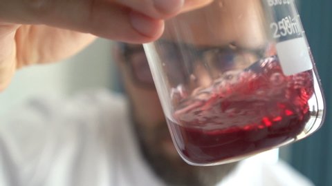 Man scientist mixing chemicals in beaker at lab, super slow motion