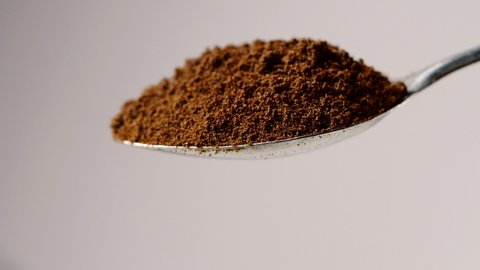 A full spoon of coffee. Coffee powder falling in slow motion from spoon