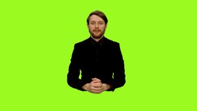 Male broadcaster is sitting at a transparent desk and talking to camera against green screen background, Chroma key, 4k shot