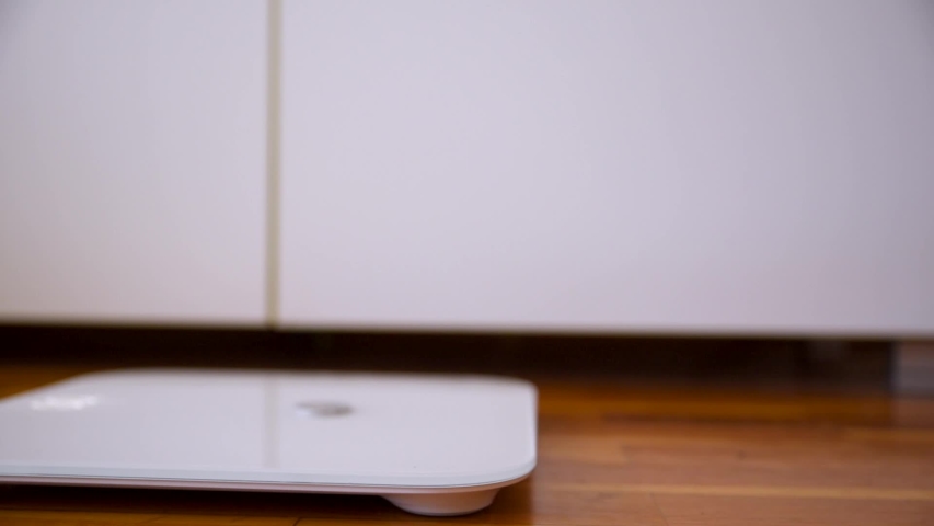 Smart scale digital measurement of body mass indoor caucasian unhealthy feet stepping up captured with dolly shot and movement
